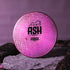 Pink and black disc golf disc with 'ASH' branding on a rock against a purple background